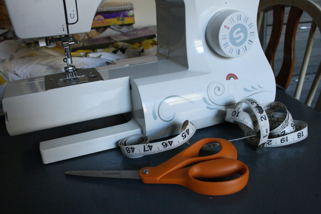 sewing machine, tape measure, and scissors on a table