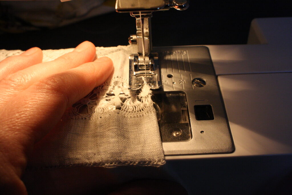 hand holding a seam while sewing fabric with a sewing machine