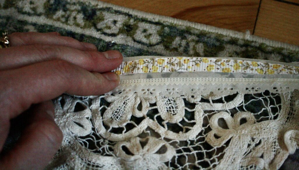 hand holding folded over lace on top of a doily