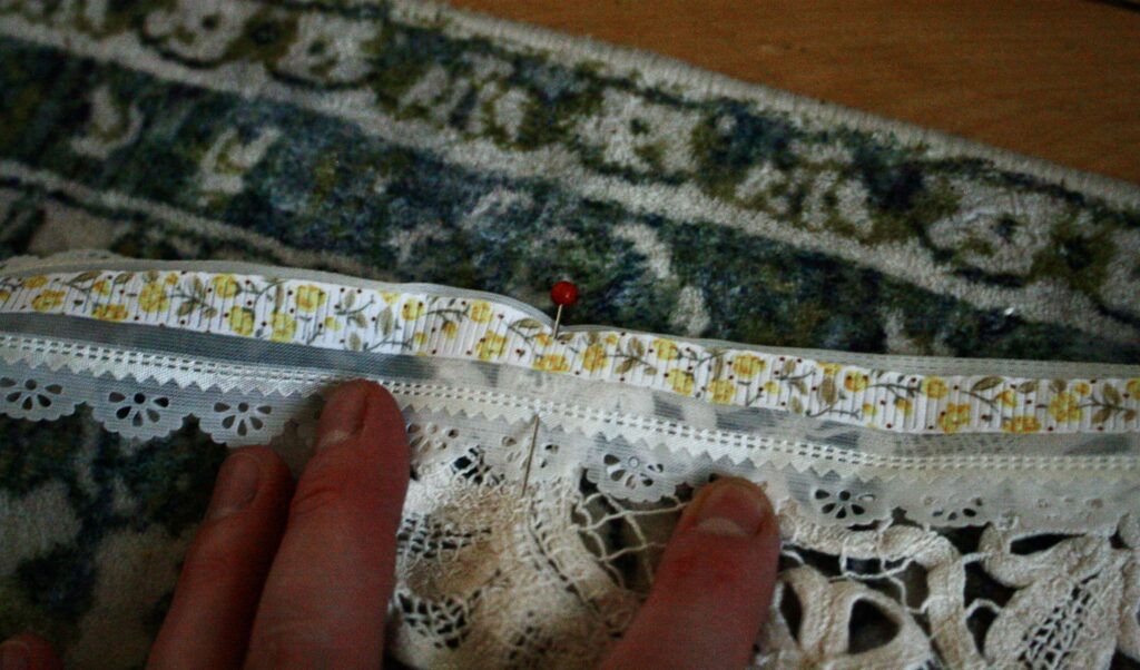 pin holding a lace doily to a lace ribbon