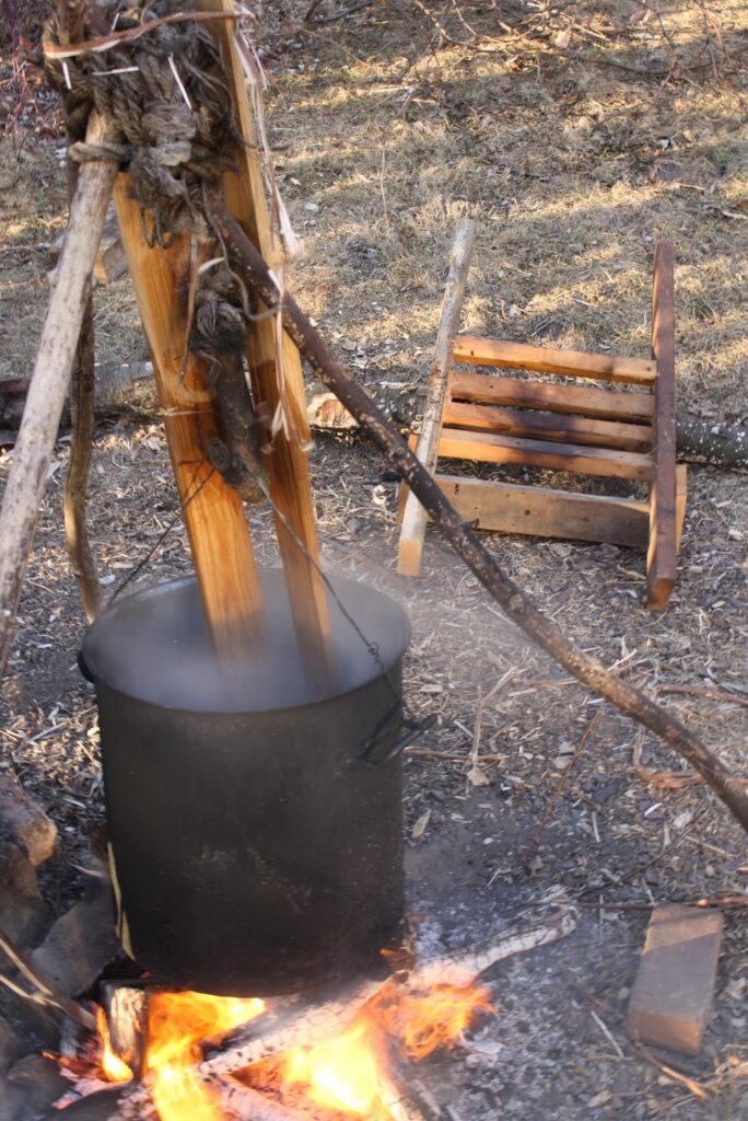 a pot of water on a fire with skis in it and a ski form sitting on the ground 