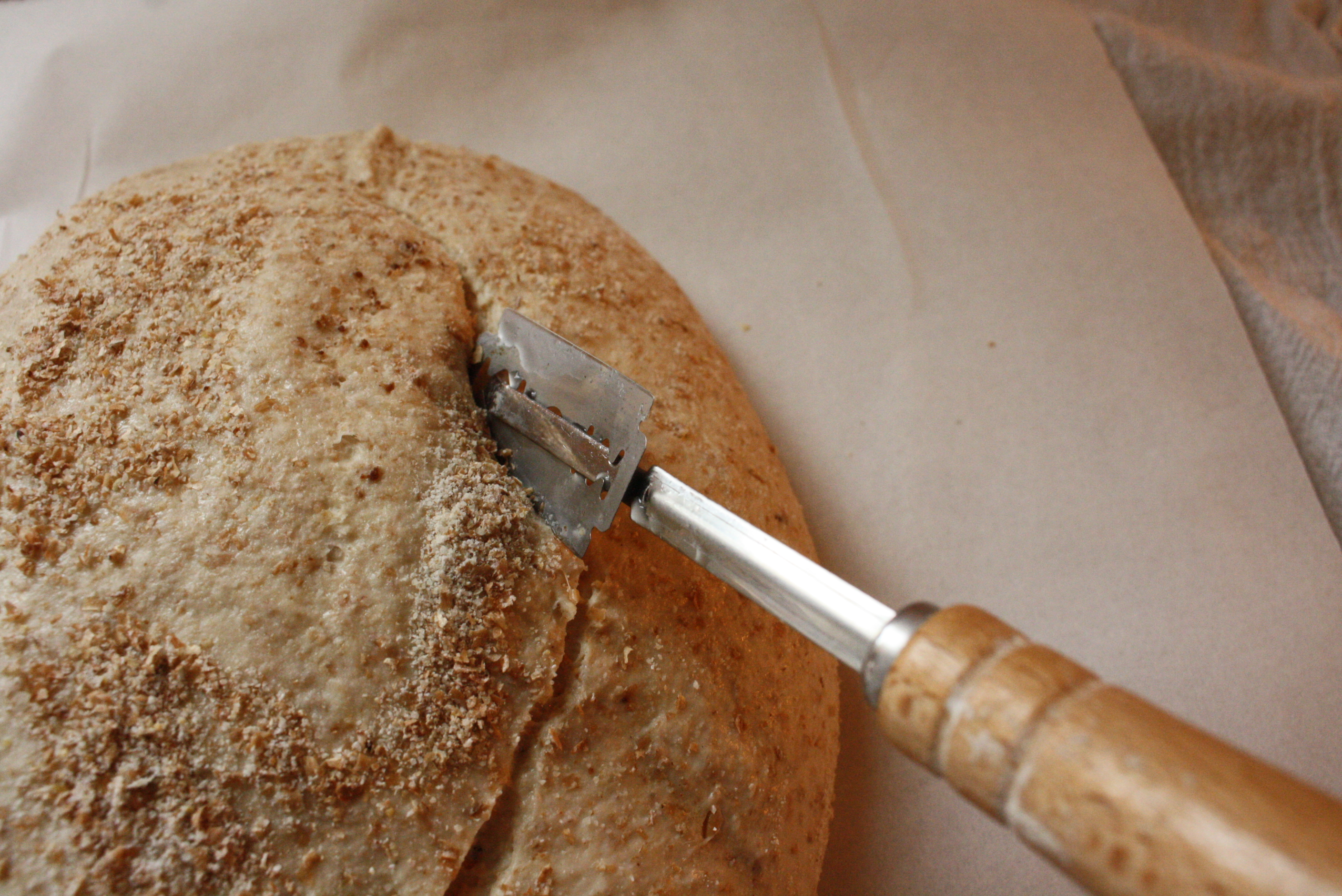 blade scoring a loaf of sourdough