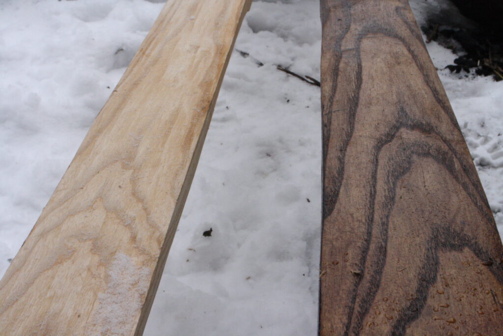 two wooden skis.  the left one is uncoated and the right one is coated with pine tar